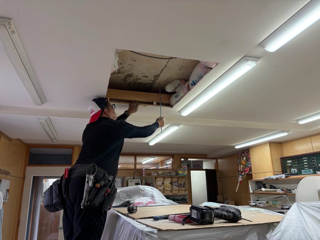 天井を開口して業務用エアコンの配管を通す作業