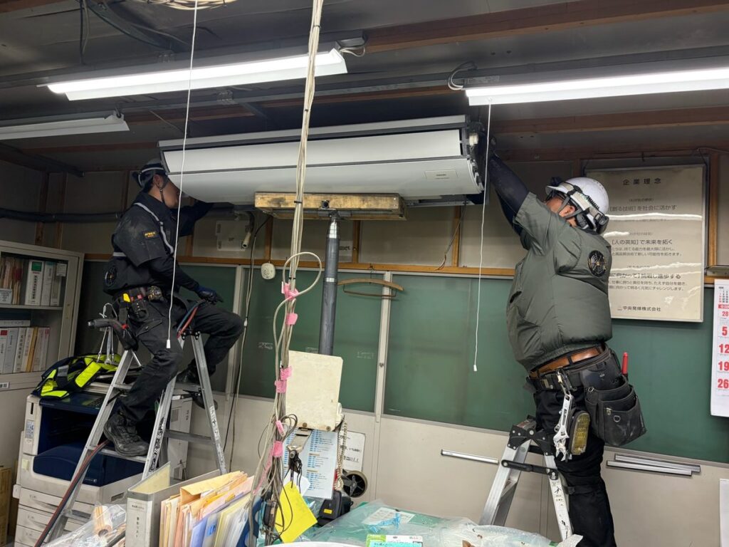 天井吊形の業務用エアコンを作業員2名で点検する定期メンテナンス