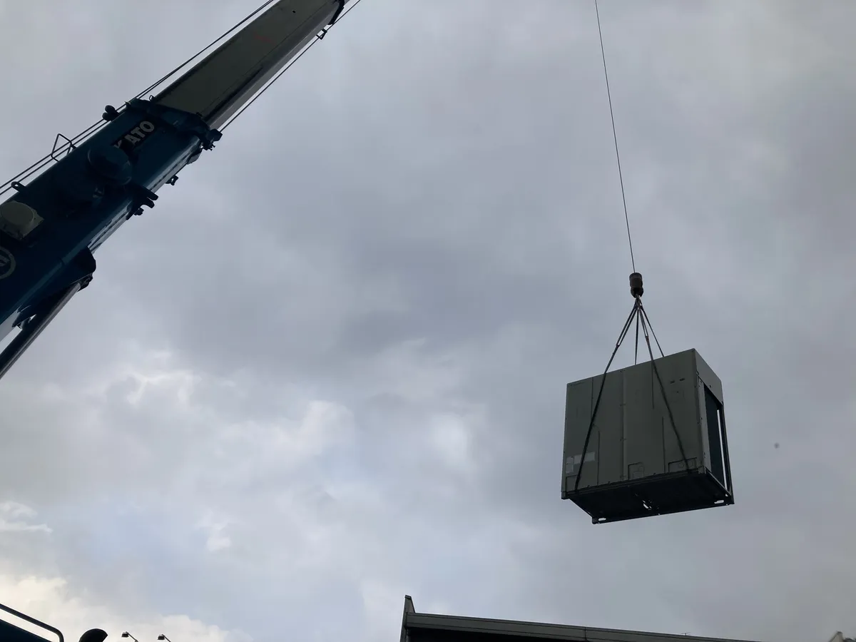 クレーンで吊り上げられる業務用エアコンの室外機