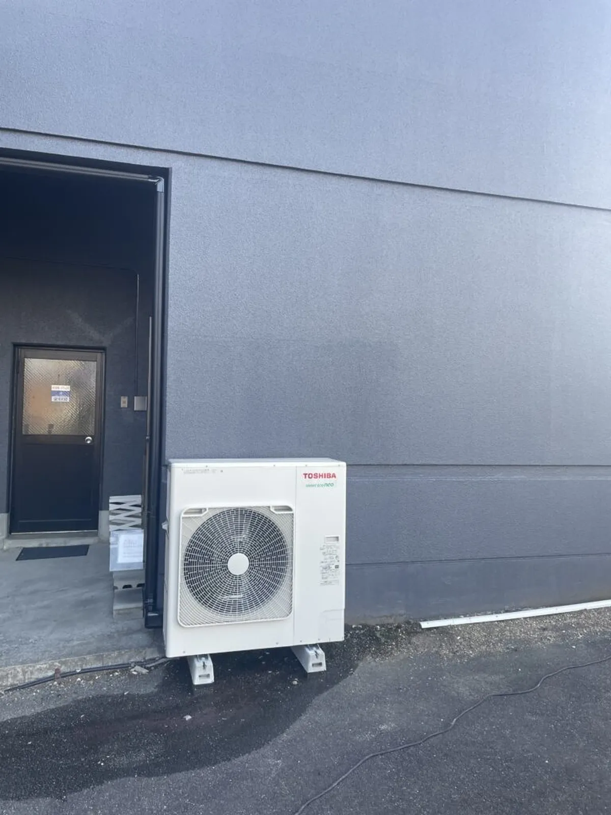 建物の外壁際の地面に設置された業務用エアコンの室外機