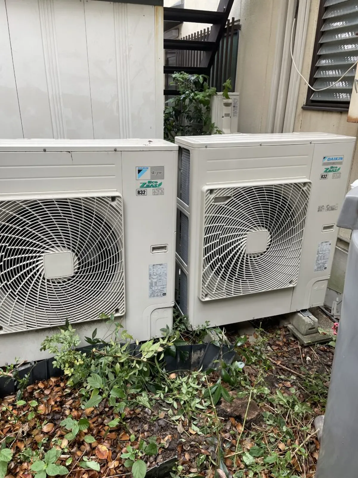 建物脇の地面に並んで設置された業務用エアコンの室外機2台