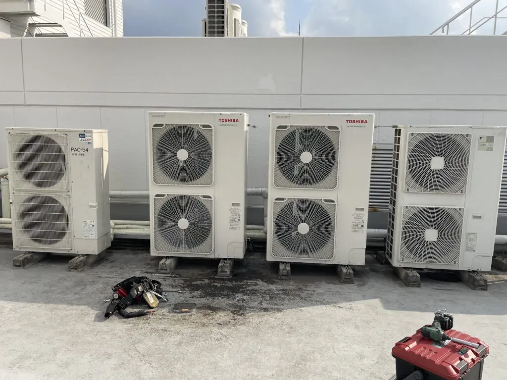 ビルの屋上に横並びで設置された業務用エアコンの室外機4台